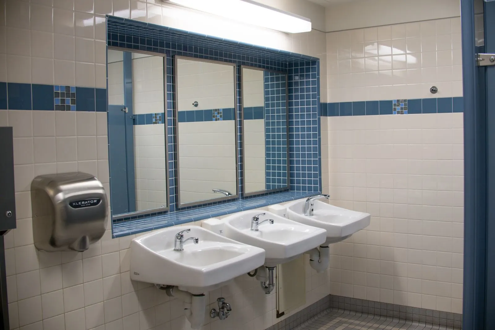 Clean commercial restroom with a row of sinks, mirrors and a hand dryer