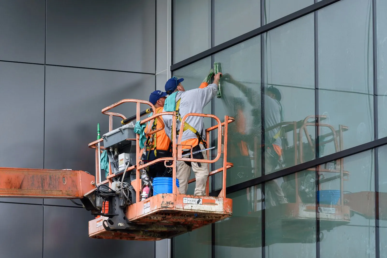 Window cleaning crew on a boom lift washing the glass of a commercial building